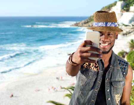 Portrait of a young african american man taking selfie at the beachの写真素材