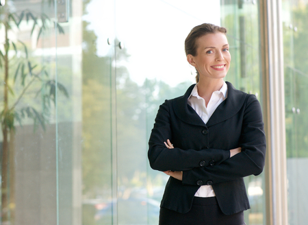 Portrait of a confident business woman smiling with arms crossed outside office building