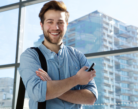 Portrait of a handsome young man smiling with mobile phoneの写真素材