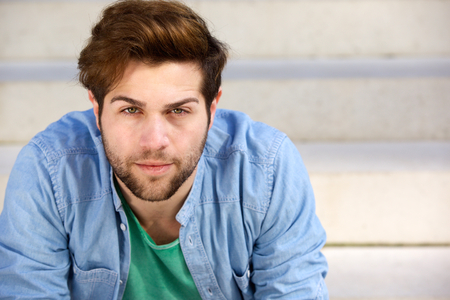 Close up portrait of a handsome young man with beard looking at cameraの写真素材