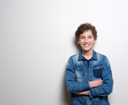 Portrait of a cheerful little boy smiling with arms crossed on white backgroundの写真素材