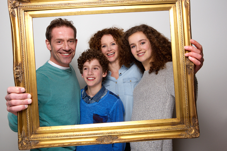 Portrait of a happy family holding picture frame and smilingの写真素材