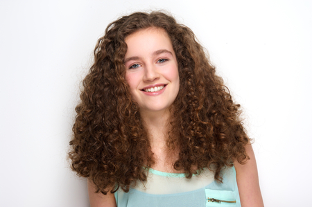 Close up portrait of a beautiful teenage girl with curly hair posing on white backgroundの写真素材