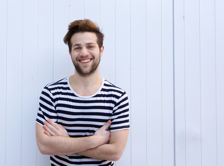 Portrait of a cute guy smiling with arms crossed on white の写真素材
