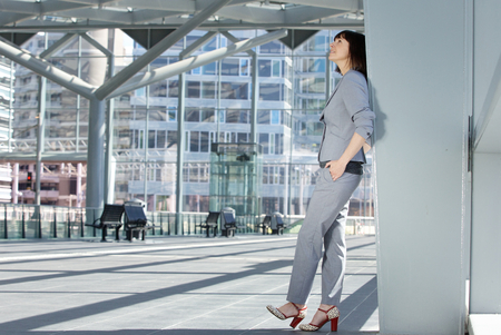 Full body side portrait of a business woman standing inside city buildingの写真素材