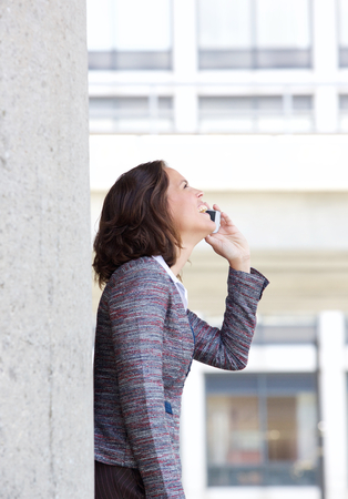 Side portrait of a cheerful business woman using mobile phoneの写真素材