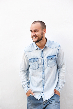 Happy guy in denim clothing standing against white wallの写真素材