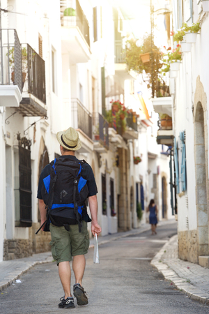 Traveling man walking with bag and map - from behindの写真素材