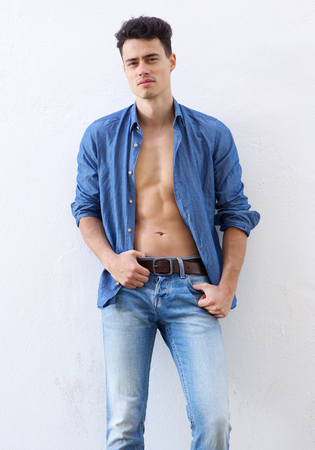Portrait of a sexy guy posing with open shirt against white backgroundの写真素材