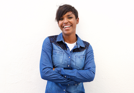 Portrait of a young smiling woman standing with arms crossed against white backgroundの写真素材