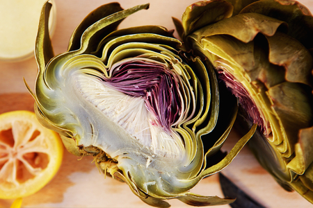 Top view close up half cut artichoke with dressing on a chopping boardの写真素材