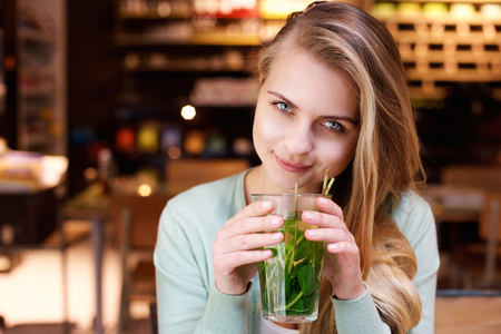 Close up portrait of an attractive young woman drinking mint teaの写真素材