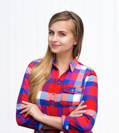 Portrait of an attractive young blond woman standing with arms crossed on white backgroundの写真素材