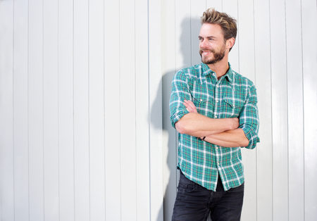 Portrait of a smiling modern man with beard standing against white backgroundの写真素材