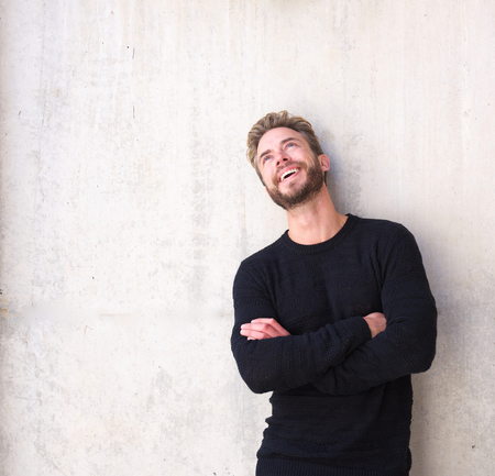 Portrait of a cheerful man laughing with arms crossed looking upの写真素材