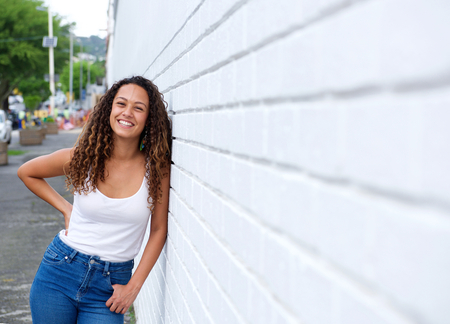 Portrait of cheerful young woman in leaning on a wall outdoors.の写真素材