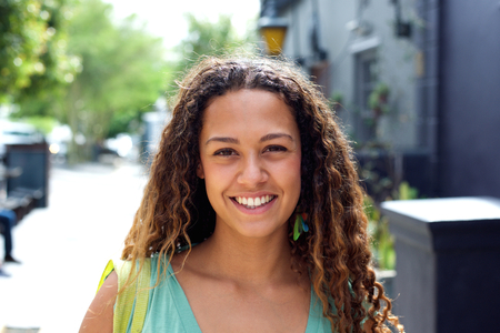 Closeup portrait of smiling young woman walking outdoors in the cityの写真素材