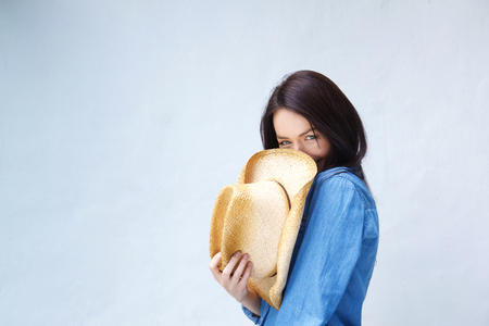 Portrait of a smiling woman covering face with cowboy hat