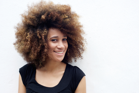Portrait of smiling young african american woman standing against white backgroundの写真素材