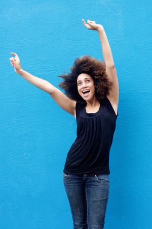 Portrait of young woman smiling with arms raisedの写真素材
