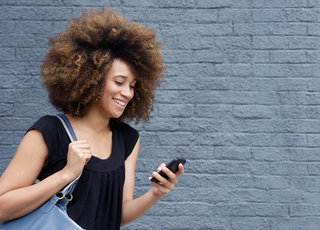 Portrait of young african american woman smiling with cellphoneの写真素材