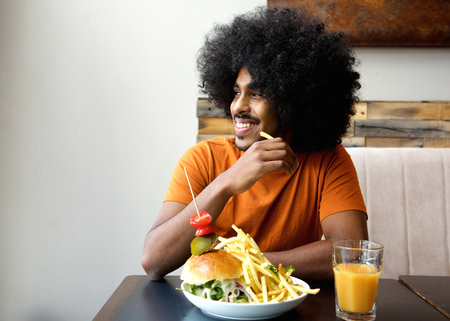 Smiling man with hamburger and fries at restaurant
