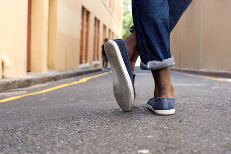 Rear view low angle man standing with crossed legsの写真素材