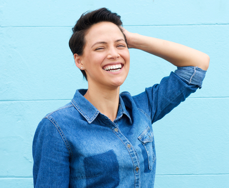 Close up portrait of a laughing woman with hand in hairの写真素材