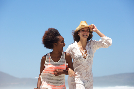 Portrait of two happy young women walking at the beach togetherの写真素材