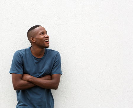 Portrait of a happy african american guy smiling with arms crossed and looking away at copy spaceの写真素材
