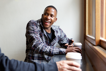 Portrait of smiling young african man sitting at cafe with a friendの写真素材