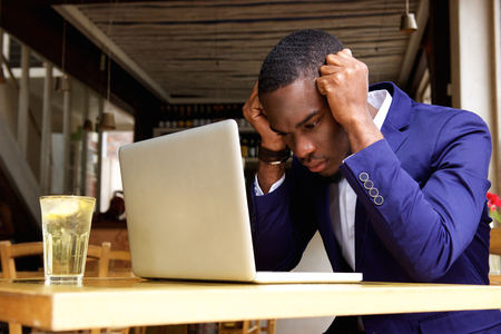 Portrait of an african businessman sitting with laptop at cafe
