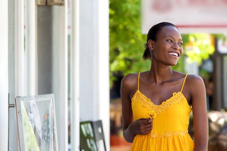 Close up portrait of attractive young african woman holding a flower walking outdoorsの写真素材