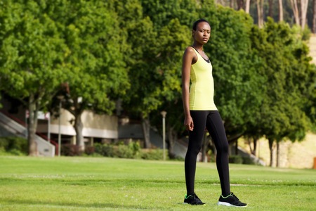 Full body portrait of fit young woman in sportswear standing outdoors in a parkの写真素材