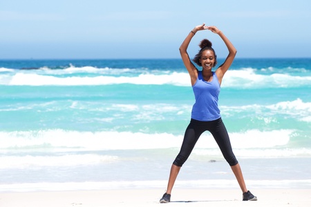 Full body portrait of young woman enjoying stretching exercise at the beach