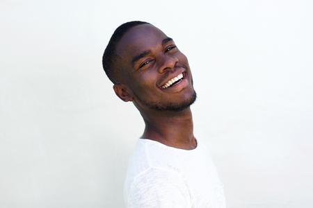 Close up portrait of cheerful young black guy laughing against white backgroundの写真素材