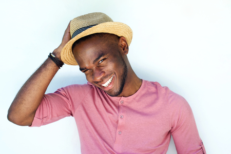 Close up portrait of smiling young african man with hat standing against white backgroundの写真素材