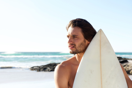 Close up side portrait of serious young surfer at the beach
