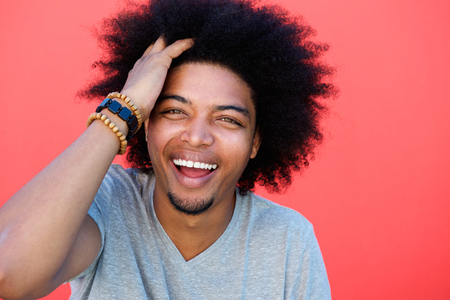 Portrait of a laughing young man with hand in afro hairの写真素材