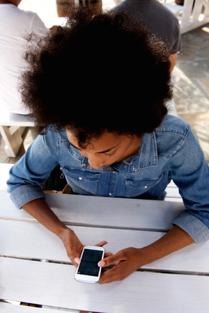 Close up portrait from above of attractive woman sitting outside surfing internet on cellphoneの写真素材