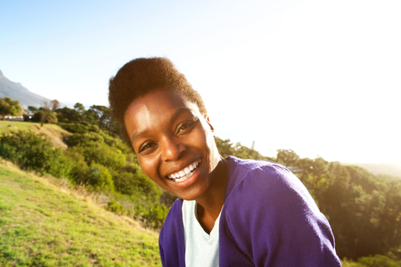 Close up portrait of beautiful young african female smiling outdoorsの写真素材