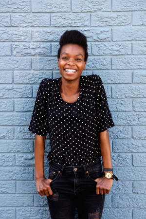 Portrait of smiling african woman standing against gray brick wallの写真素材