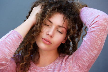 Close up portrait of beautiful girl with hands in hair and eyes closedの写真素材