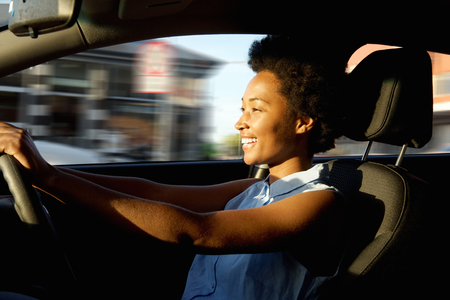 Side portrait of happy young african woman driver driving a carの写真素材