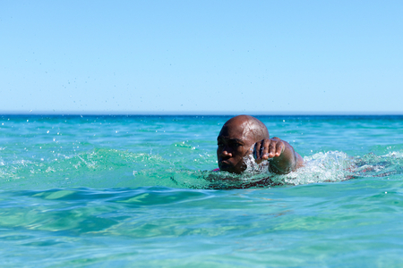 Portrait of healthy young african guy swimming in ocean waterの写真素材