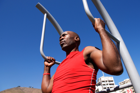 Close up portrait of young african man exercising outdoors with exercise equipment at the parkの写真素材