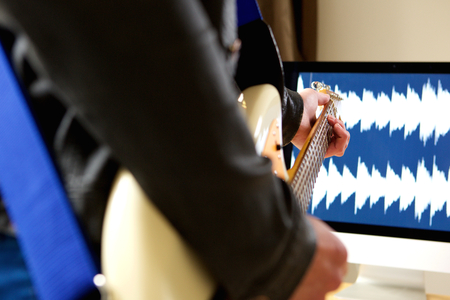 Close up portrait of man playing guitar with computer in backgroundの写真素材
