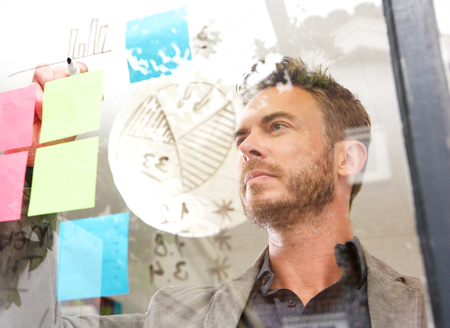 Portrait of serious business man drawing diagram on idea board