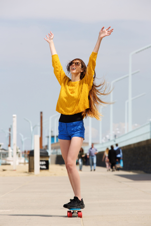 Portrait of woman riding skateboard with hands outstretchedの写真素材