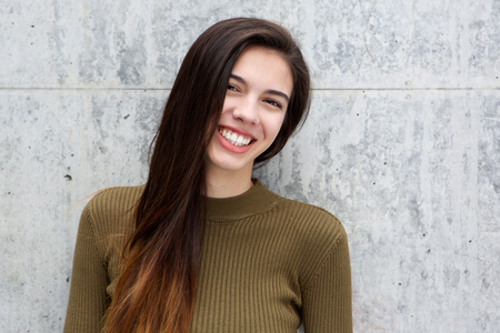 Portrait of smiling young woman against gray wallの写真素材